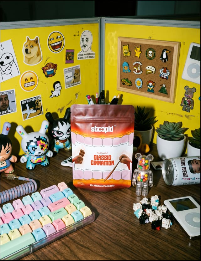 Stoopid Classic Cinnamon pouch on a desk with collectible toys, mechanical keyboard, and stickers